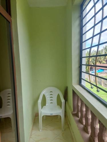 a white chair sitting in a room with a window at JOLANDA STUDIO APARTMENTs in Mtwapa