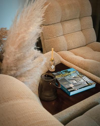 a book and candle on a coffee table on a couch at Hôtel Latécoère in Biscarrosse