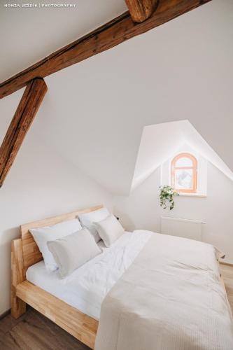 a white bedroom with a bed with white sheets and pillows at Penzion Za Stromem in Opočno