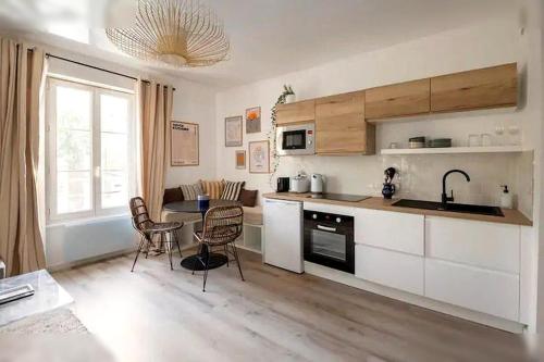 une cuisine avec des armoires blanches et une table avec des chaises dans l'établissement Logement St Malo Centre - Emplacement idéal 20 min à pied Intra-Muros & grande plage du Sillon, à Saint-Malo