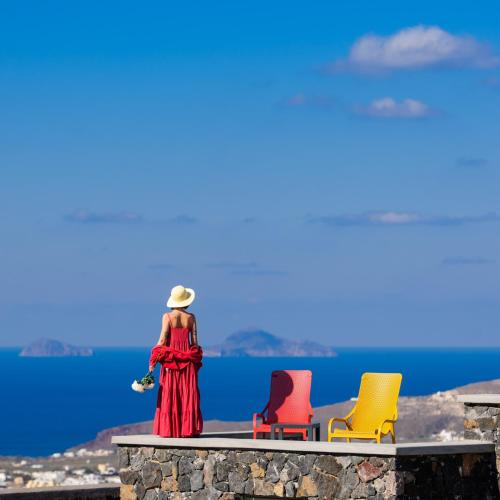 a woman in a red dress standing next to three chairs at Avan Luxury Villas in Pyrgos