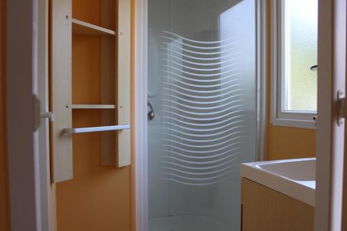 a bathroom with a glass shower door next to a sink at Camping Le Balcon de Chartreuse in Miribel-les-Échelles