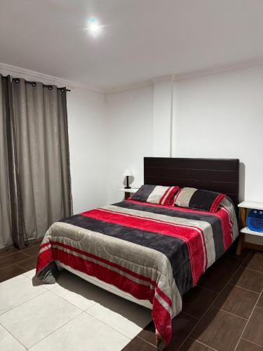 a bedroom with a bed with a red and black blanket at Santino Apart in Puerto Iguazú
