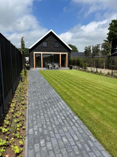 a house with a brick walkway in front of a yard at Vakantiehuis Het Paradijs in Barneveld in Barneveld