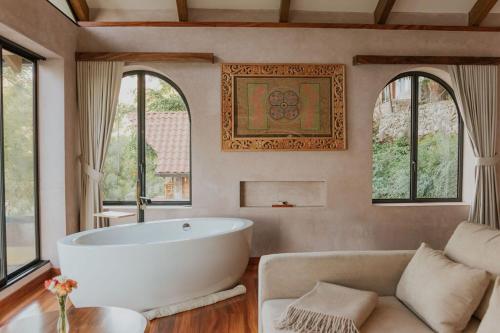 a bathroom with a tub and a couch and windows at Luxury Lakefront Retreat at Casa Floresta in San Marcos La Laguna