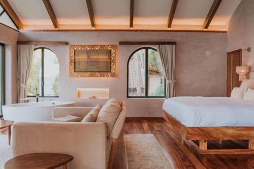a bedroom with a bed and a couch and a tub at Luxury Lakefront Retreat at Casa Floresta in San Marcos La Laguna