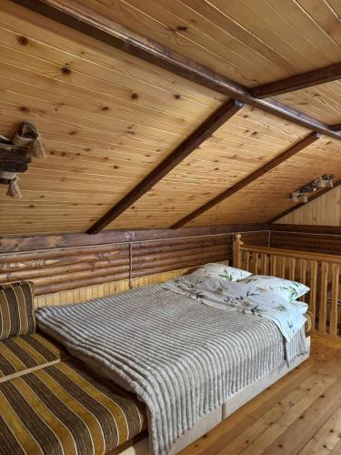 a bed in a room with a wooden ceiling at Карпатська Модрина in Kosiv