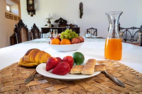 a table with a plate of fruit and croissants and bread at Casa das Jardas in Idanha-a-Nova