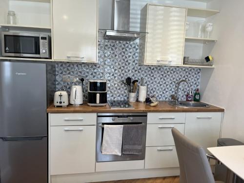 a kitchen with white cabinets and a stainless steel refrigerator at Bayside at 9 The Dome Barton on Sea in Barton on Sea