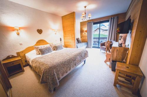 a bedroom with a bed and a large window at Chalet Hôtel Les Airelles in Pralognan-la-Vanoise