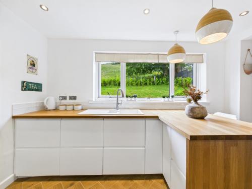 a white kitchen with a sink and a window at 5-Bed Retreat with Hot Tub, Garden & Relaxing Views in Burry Port