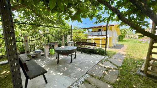 Un patio con parrilla, mesa y bancos. en Olive Garden House, en Izola