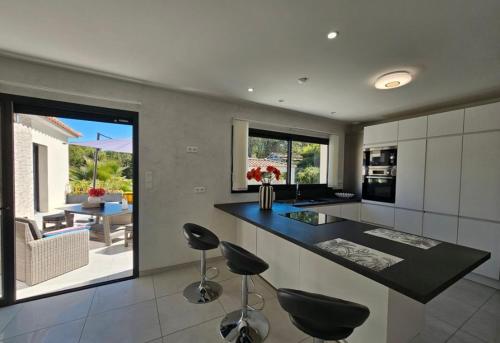 une cuisine avec deux tabourets de bar et un comptoir dans l'établissement Magnifique, villa, spacieuse et lumineuse, à Rocbaron