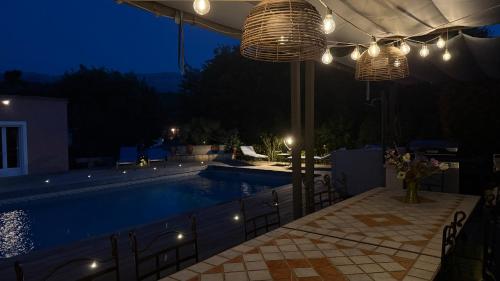 une piscine la nuit avec un grand parasol dans l'établissement Maison d'hôtes Hippone, à Nans-les-Pins