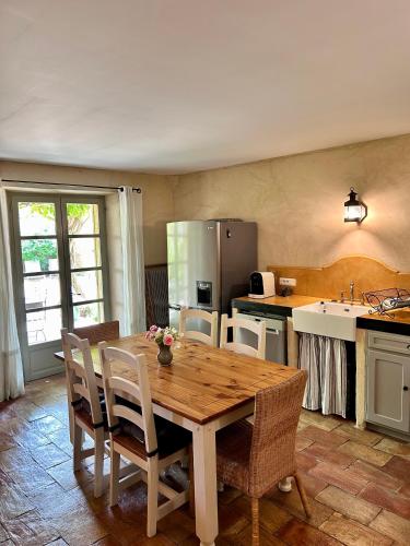 une cuisine avec une table et des chaises en bois ainsi qu'une cuisine avec un évier dans l'établissement La maison de Nôtre Dame 6, à Aigaliers