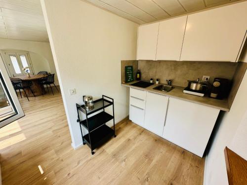 a kitchen with white cabinets and a wooden floor at Casa Papavero in Gambarogno