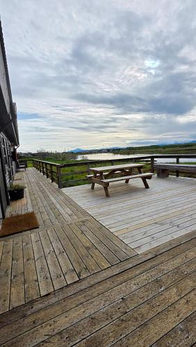 una terrazza in legno con due tavoli da picnic di Riverfront Lodge Hella a Hella