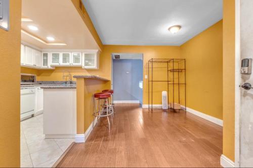 a kitchen with yellow walls and white cabinets and red stools at Condo Near LAX & Sofi in Los Angeles