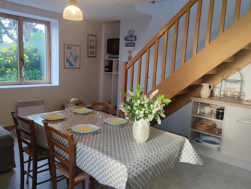 une table de salle à manger avec un vase de fleurs dessus dans l'établissement gite proche de la ria d'ETEL, à Plouhinec