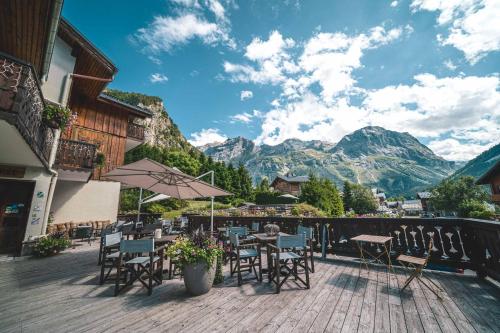 a patio with chairs and tables with mountains in the background at Chalet Hôtel Les Airelles in Pralognan-la-Vanoise