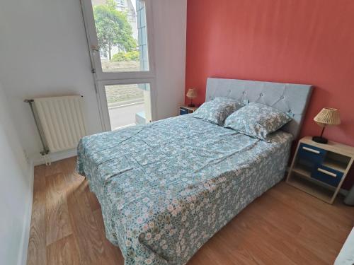 une chambre avec un lit avec une couette bleue et une fenêtre dans l'établissement La Frégate, à Saint-Malo