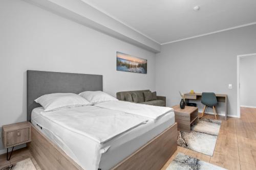 a white bedroom with a bed and a desk at Domloge Lofts & Apartments in Cologne