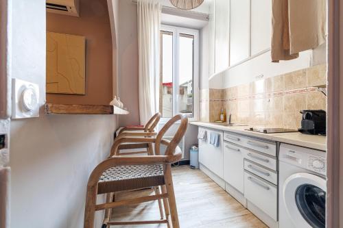 une cuisine avec trois chaises et une machine à laver dans l'établissement L'Échappée Cannoise Forville, à Cannes