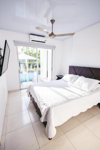 a white bedroom with a bed and a ceiling fan at Casa Quinta Carmen de Apicala in Carmen de Apicalá