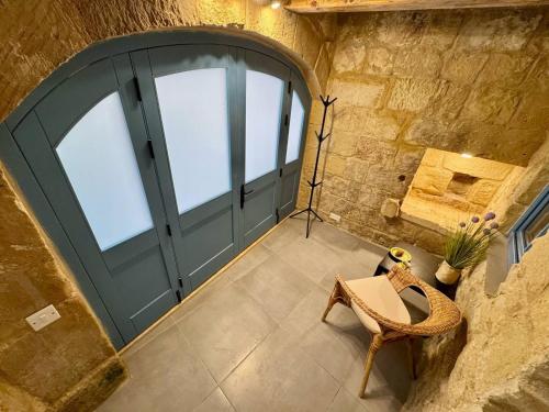 a large green door in a stone building with a chair at Kappella boutique in Malta in Żurrieq