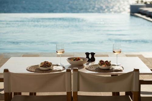 a table with two plates of food and glasses of wine at Porto Mykonos in Mýkonos City