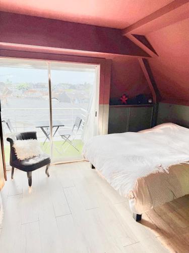 - une chambre avec un lit, une chaise et un balcon dans l'établissement Appartement type loft La Baule centre, à La Baule
