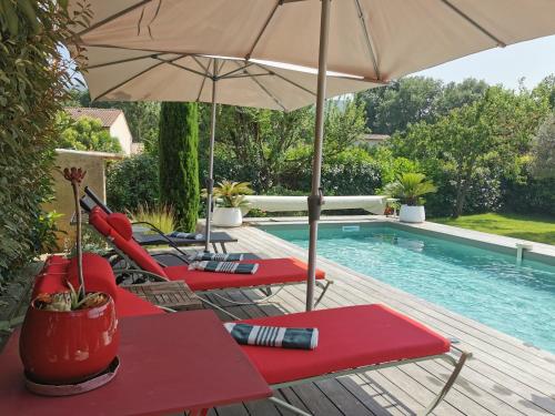 deux chaises et un parasol à côté d'une piscine dans l'établissement Maison 3 étoiles Piscine chauffée Centre Var, à Gonfaron