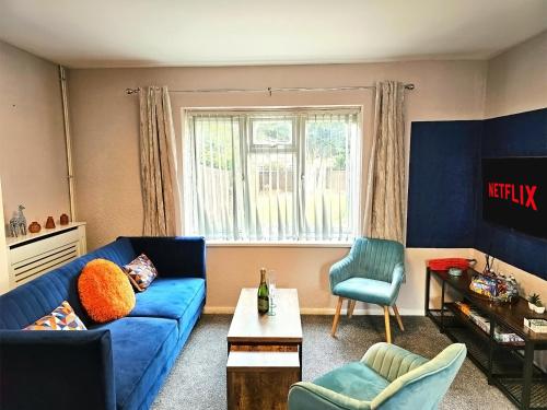 a living room with a blue couch and a window at Group Stay with 3 Parking Spaces in Banbury