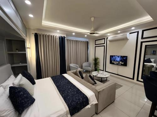 a bedroom with a bed and a couch and a tv at High Rise Executive Luxurious Apartments Facing Centaurus Mall - LMY Islamabad in Islamabad