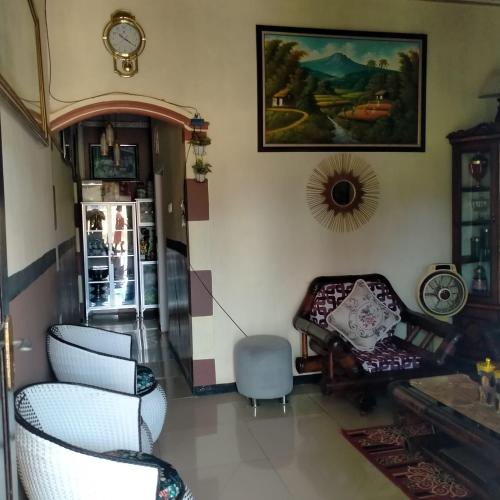 a living room with chairs and a clock on the wall at Misran Homestay in Triwung