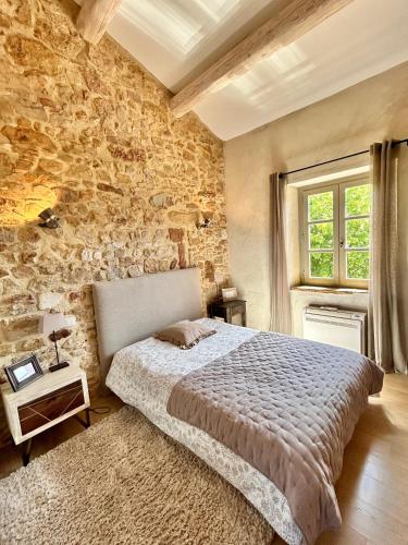 une chambre avec un lit et un mur en pierre dans l'établissement Gîte les hirondelles, à Aigaliers