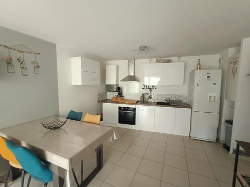 une cuisine avec une table et un réfrigérateur blanc dans l'établissement Appartement T3 garage privé terrasse, à Toulon