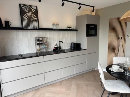 バルネフェルトにあるVakantiehuis Het Paradijs in Barneveldの白いキャビネットとテーブル付きのキッチン