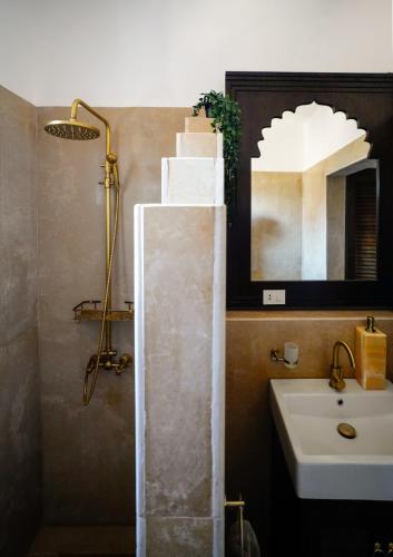 a bathroom with a shower and a sink and a mirror at Al Wadi Boutique Hotel in Al Aqālitah