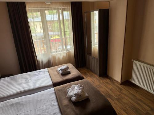a bedroom with two towels on a bed with a window at Hotel Svanseti in Mestia