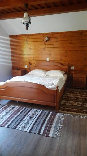 a bed in a bedroom with a wooden wall at Casa Boris in Bîrsana