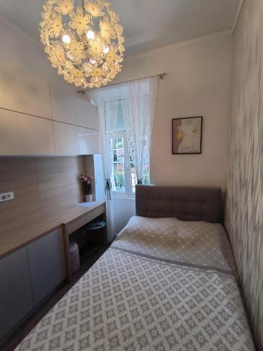 a small bedroom with a bed and a chandelier at Apartman Beti in Opatija