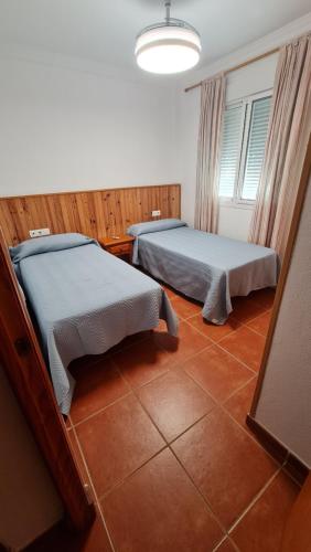 a bedroom with two beds and a window and a lamp at Vaca House in El Puerto de Santa María