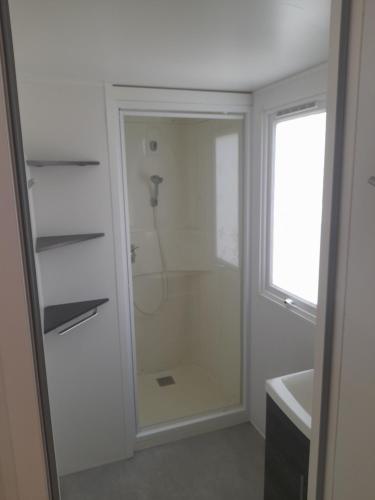 une salle de bain avec une douche avec une porte vitrée dans l'établissement Mobil-Home VI07 Camping La Carabasse VIAS-PLAGE, à Vias