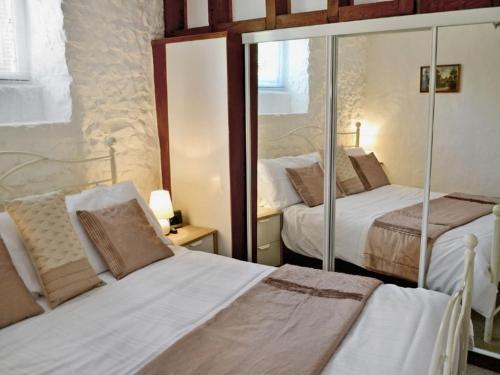 ein Schlafzimmer mit zwei Betten und einem Spiegel in der Unterkunft Yarde cottage rural Devon Dog friendly in Membury