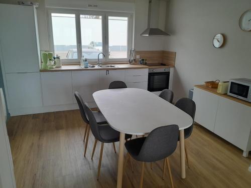 une table blanche et des chaises dans une cuisine avec une fenêtre dans l'établissement Wissant-sur-Mer, à Wissant