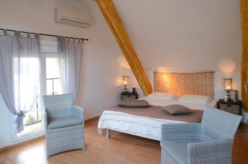 a bedroom with a large bed and two chairs at Chambre d'hôtes au Domaine de la Moretie in Cublac