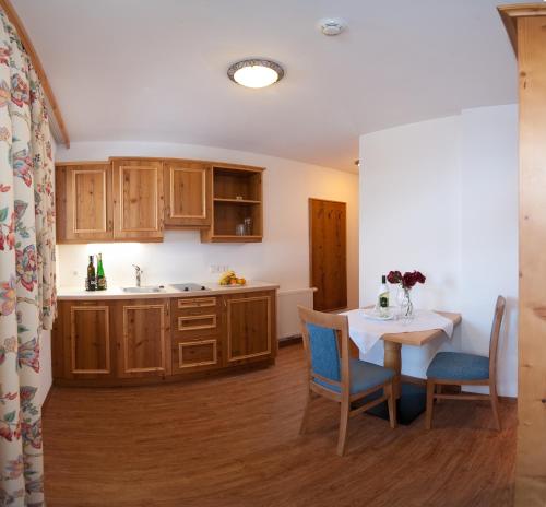 a kitchen with wooden cabinets and a table and chairs at Naturhotel Hüttenwirt im Grossarltal in Hüttschlag
