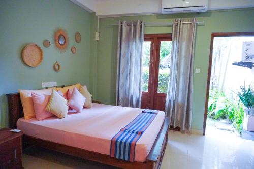 a bedroom with a bed with pink and blue pillows at 7elements - Boutique Hotel & Restaurant in Weligama