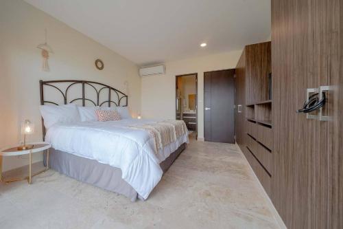 a bedroom with a large bed and a wooden cabinet at Condo Verde Oasis - Central 2 bedroom with pool, gym, private terrace - At Veranto Condos in Playa del Carmen